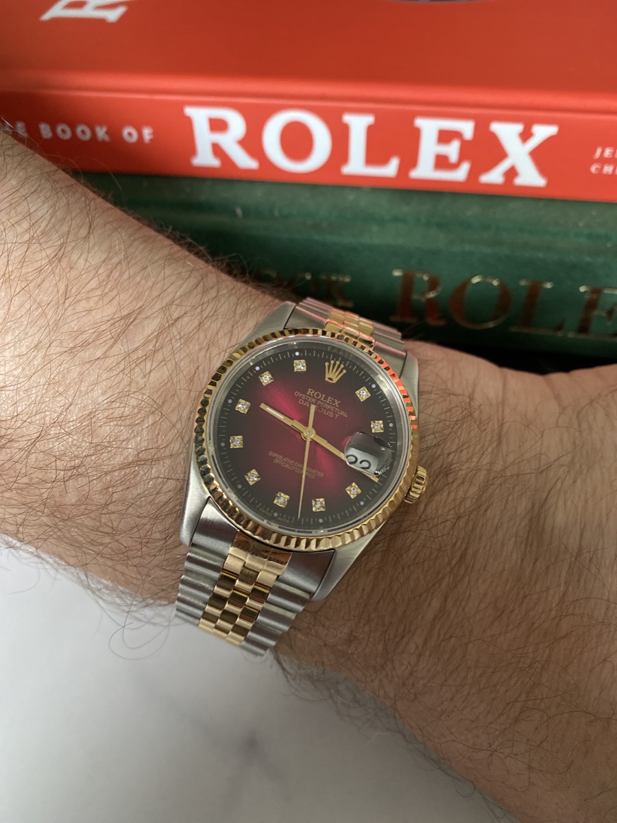 Two-tone Rolex Datejust with a red diamond-set dial, worn on the wrist
